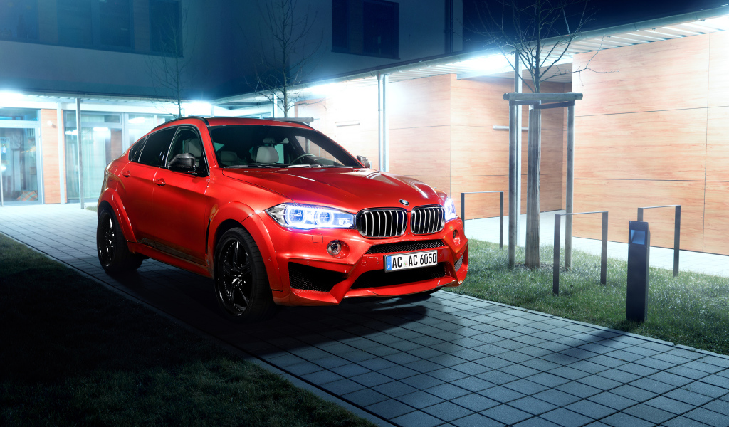 Красный автомобиль BMW X6 на тротуаре