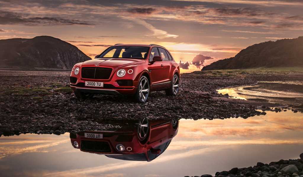 Красный автомобиль Bentley Bentayga V8, 2018 года на фоне заката 