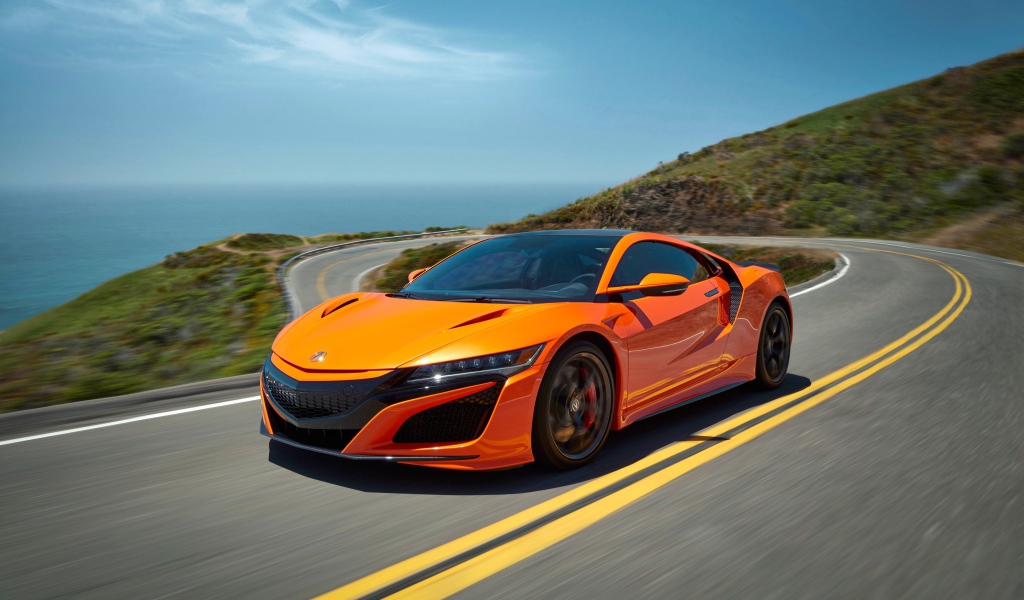 Оранжевый автомобиль Honda NSX на трассе под голубым небом