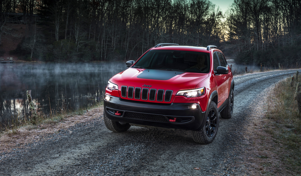 Красный автомобиль Jeep Cherokee Trailhawk, 2019 на дороге у реки
