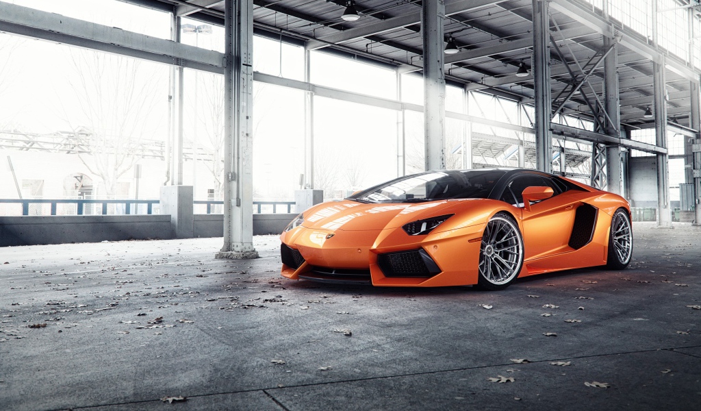 Оранжевый автомобиль Lamborghini Aventador под мостом