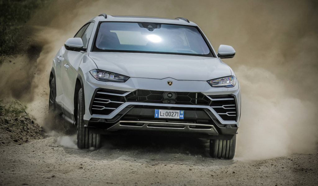Белый автомобиль Lamborghini Urus  2018 года едет по дороге 