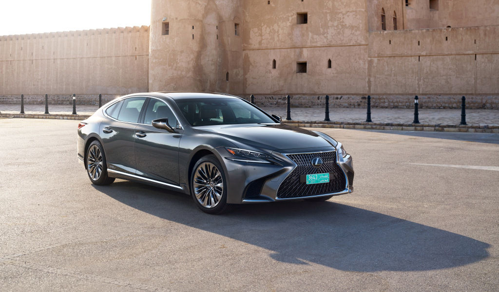 Стильный автомобиль Lexus LS 500h AWD, 2018 на фоне крепости