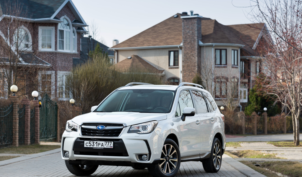 Белый автомобиль Subaru  Forester на улице у домов