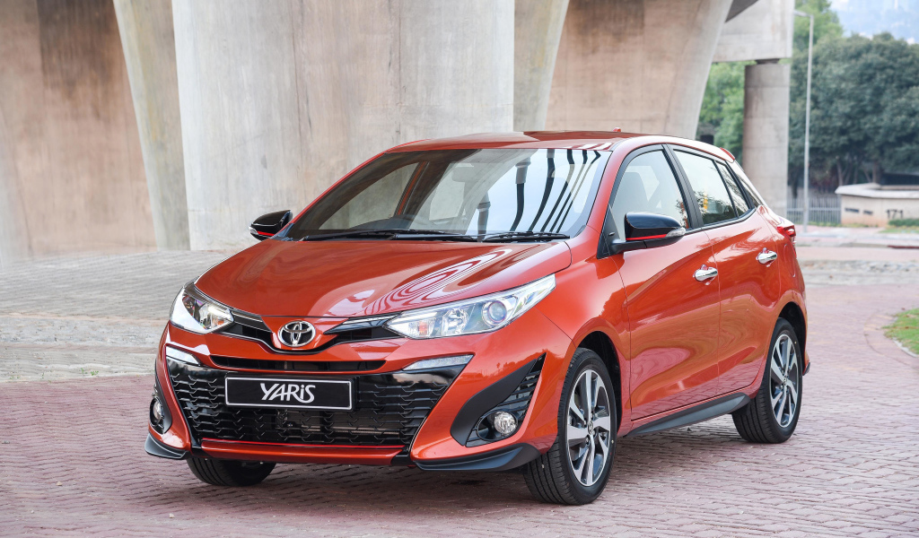 Красный автомобиль Toyota Yaris под мостом 