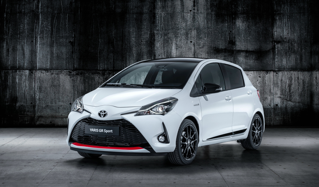 Белый автомобиль Toyota Yaris на сером фоне 