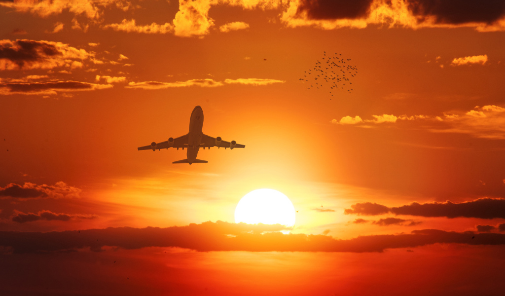 Самолет в небе на фоне солнца на закате
