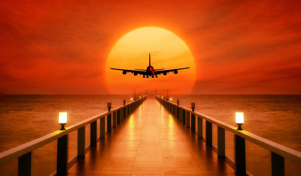 Самолет идет на посадку на закате солнца над океаном