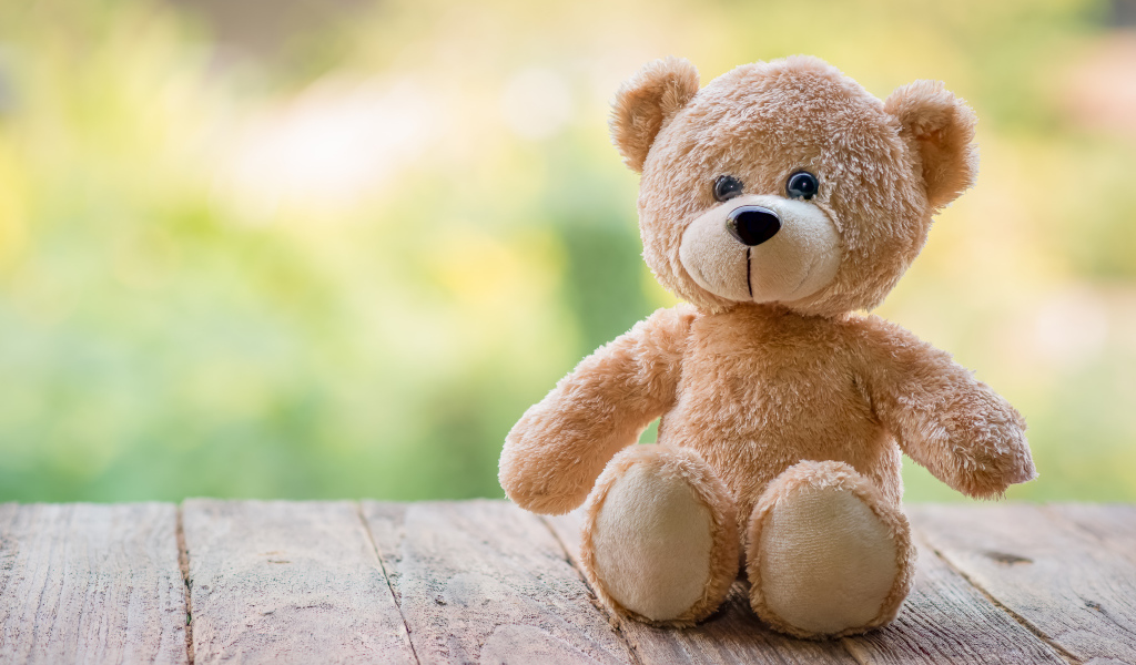 Плюшевый медведь сидит на деревянных досках