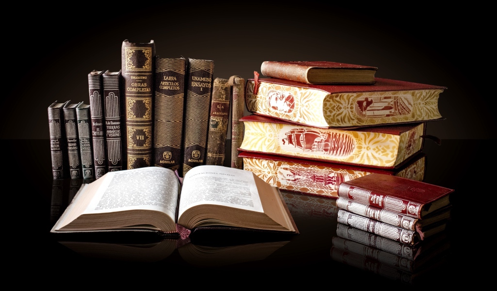 Красивые книги отражаются в зеркальной поверхности стола