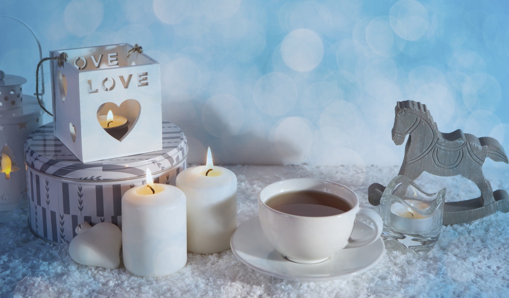 Свечи, чашка чая и фигура лошади на столе 