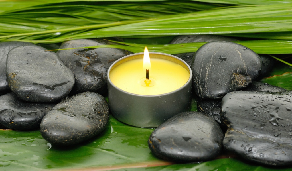 Зажженная свеча и черные камни для SPA