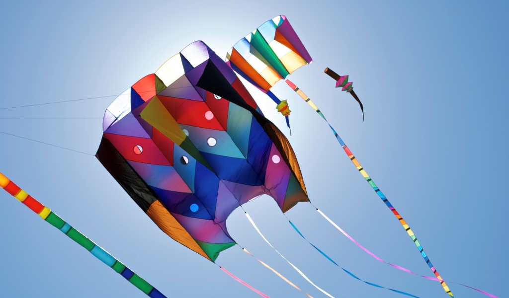 Разноцветный воздушный змей в голубом небе в лучах солнца