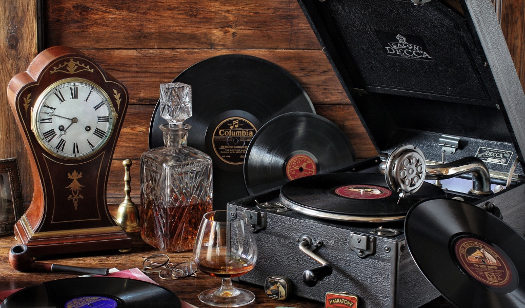 Старый граммофон с виниловыми пластинками, часами и коньяком на столе