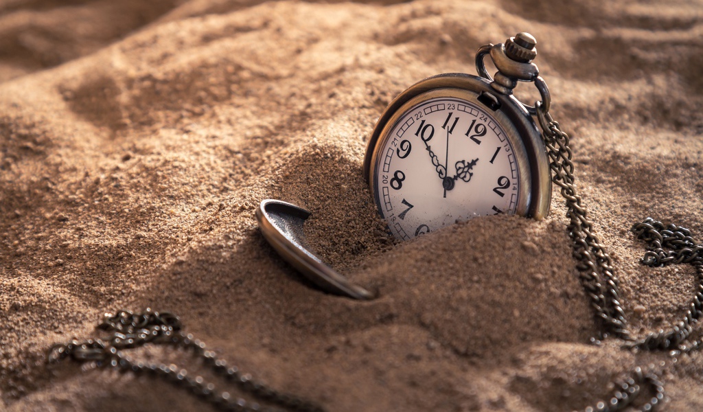Карманные часы на цепочке в песке 