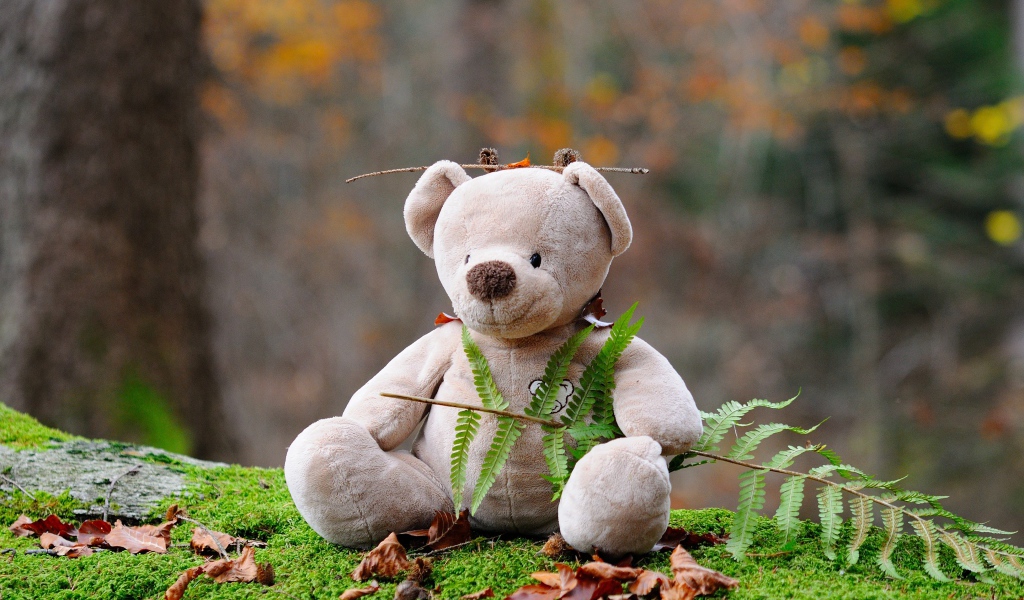 Медвежонок Тедди сидит в лесу на покрытой мхом земле