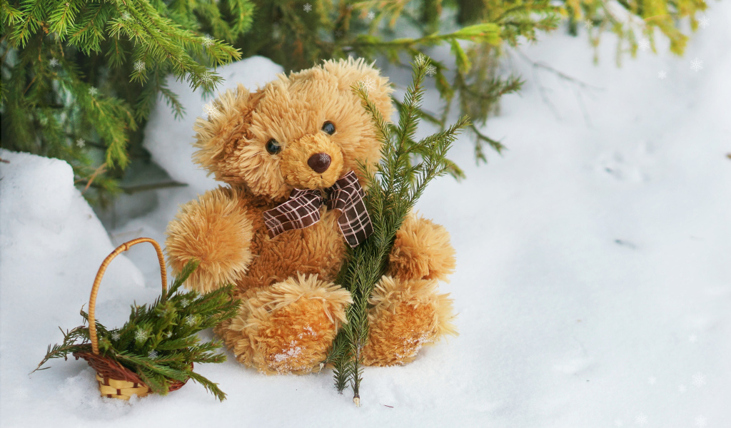 Плюшевый медвежонок на снегу с еловыми ветками
