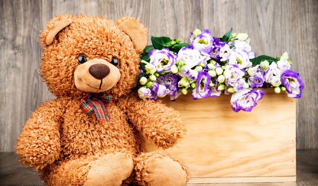 Плюшевый мишка с букетом цветов на деревянном фоне