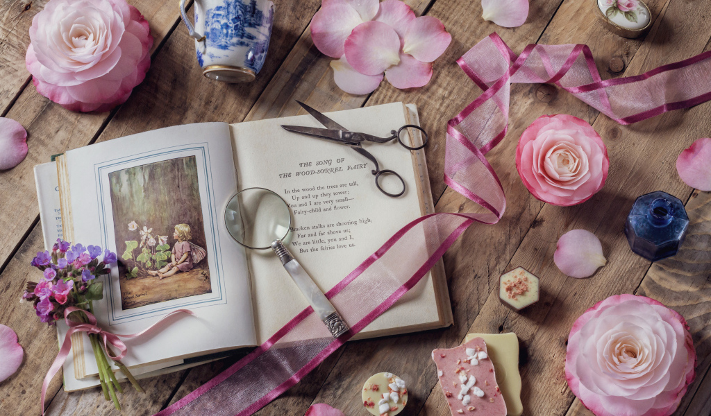 Старая книга на столе с увеличительным стеклом и искусственными цветами