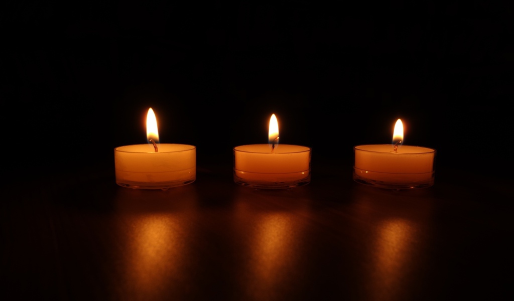 Три зажженные свечи на черном фоне