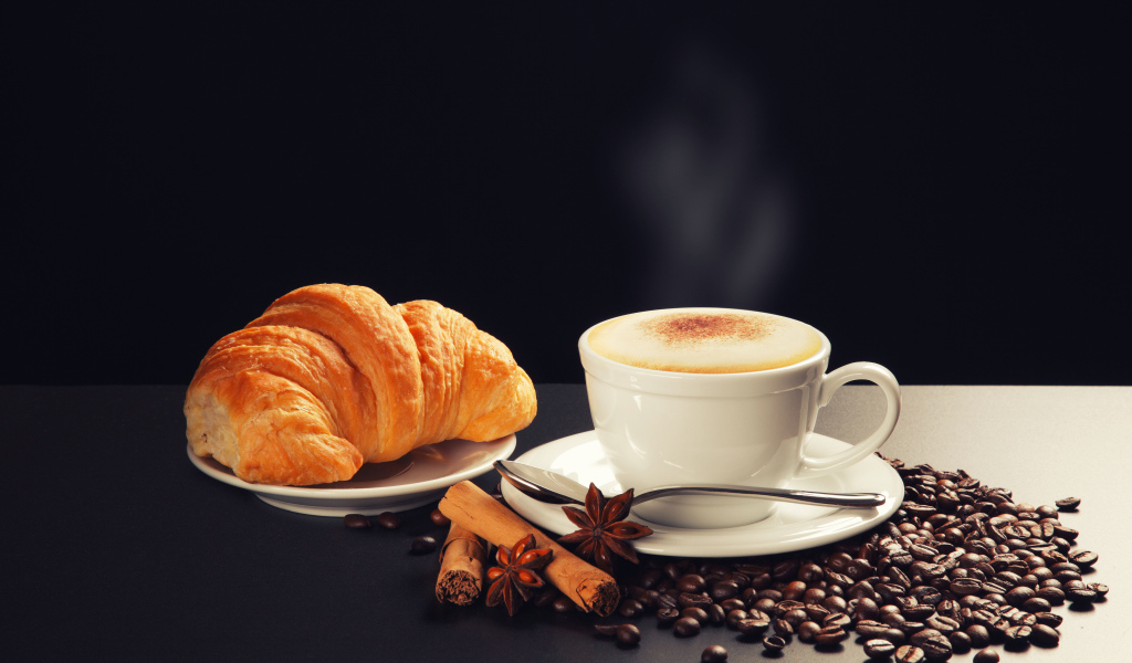A cup of coffee on the table with coffee beans, star anise, cinnamon croissant