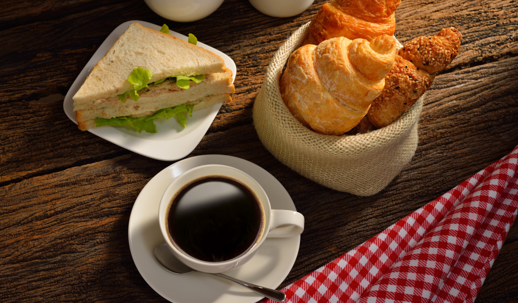 Чашка кофе с круассанами и сендвичем на завтрак