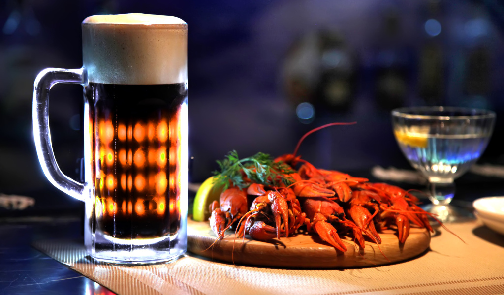 Бокал пива с вареными раками на столе