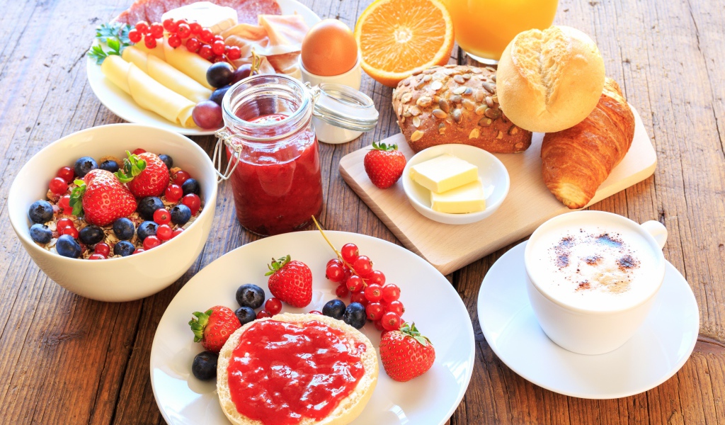 Аппетитный завтрак на столе с бутербродами, кофе и ягодами