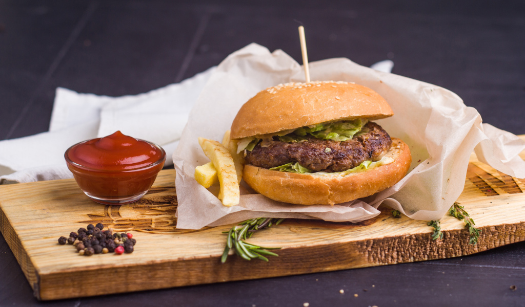 Аппетитный гамбургер с картофелем фри и кетчупом на столе