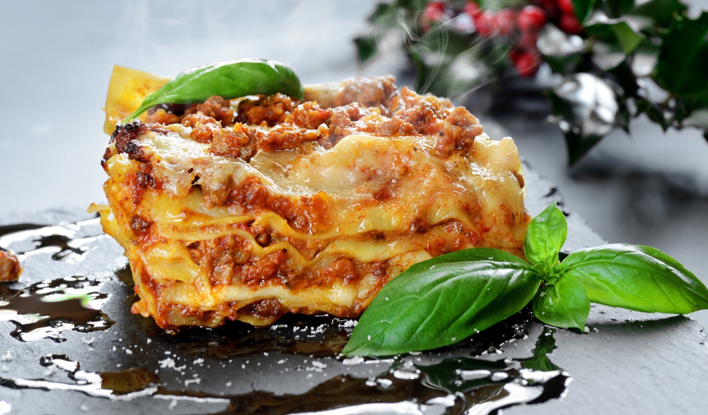 Аппетитная горячая лазанья с базиликом на столе