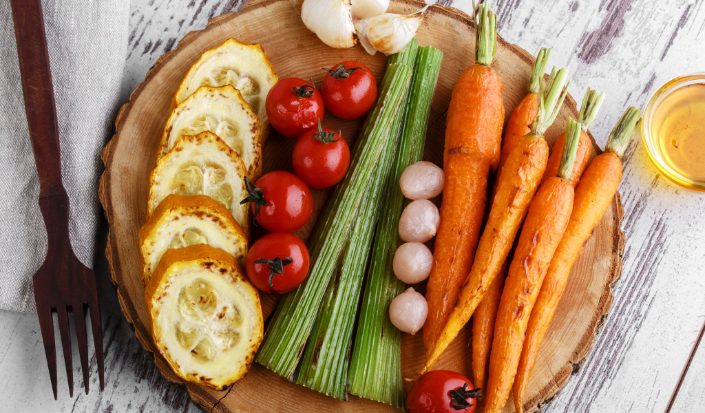 Печеные кабачки, помидоры, морковь, сельдерей и чеснок на разделочной доске