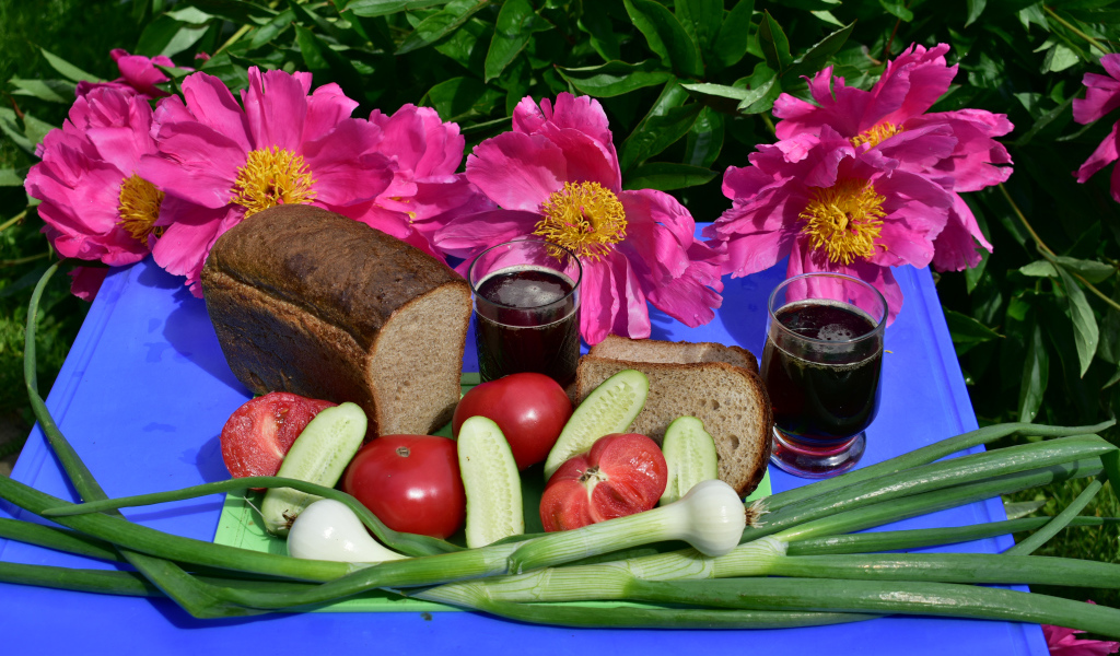 Черный хлеб, овощи и вино на фоне розовых пионов 