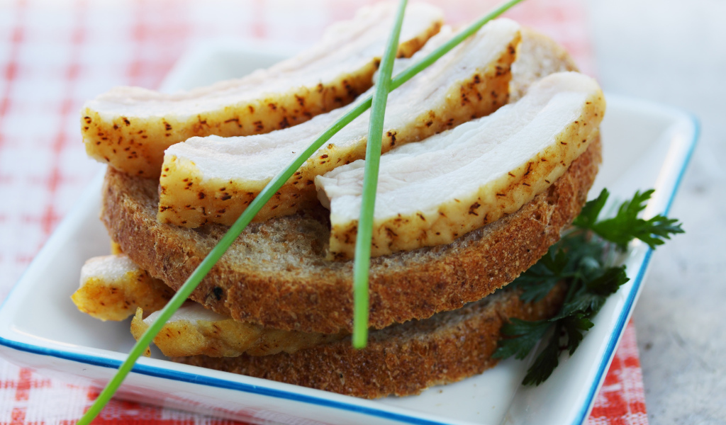 Черный хлеб с салом и зеленью на столе