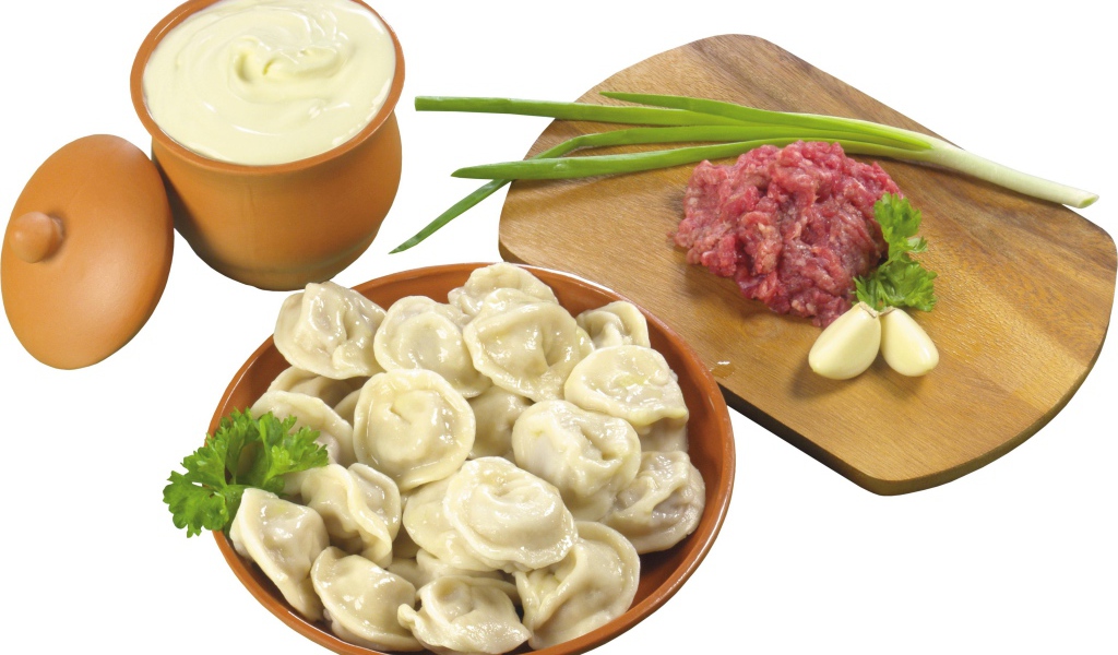 Boiled dumplings on the table with minced meat, sour cream and green onions