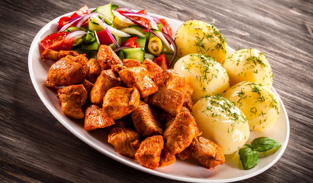 Вареный картофель с мясом и салатом на тарелке