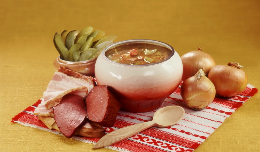 Борщ на столе с мясом, солеными огурцами и луком