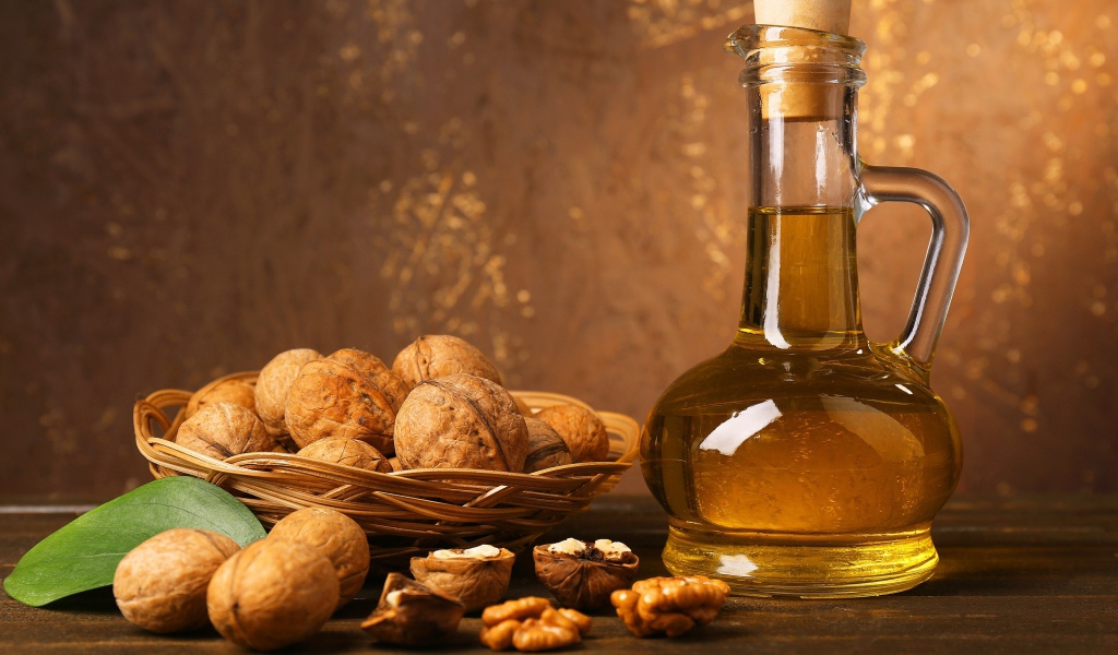 Масло в стеклянной бутылке на столе с грецкими орехами 