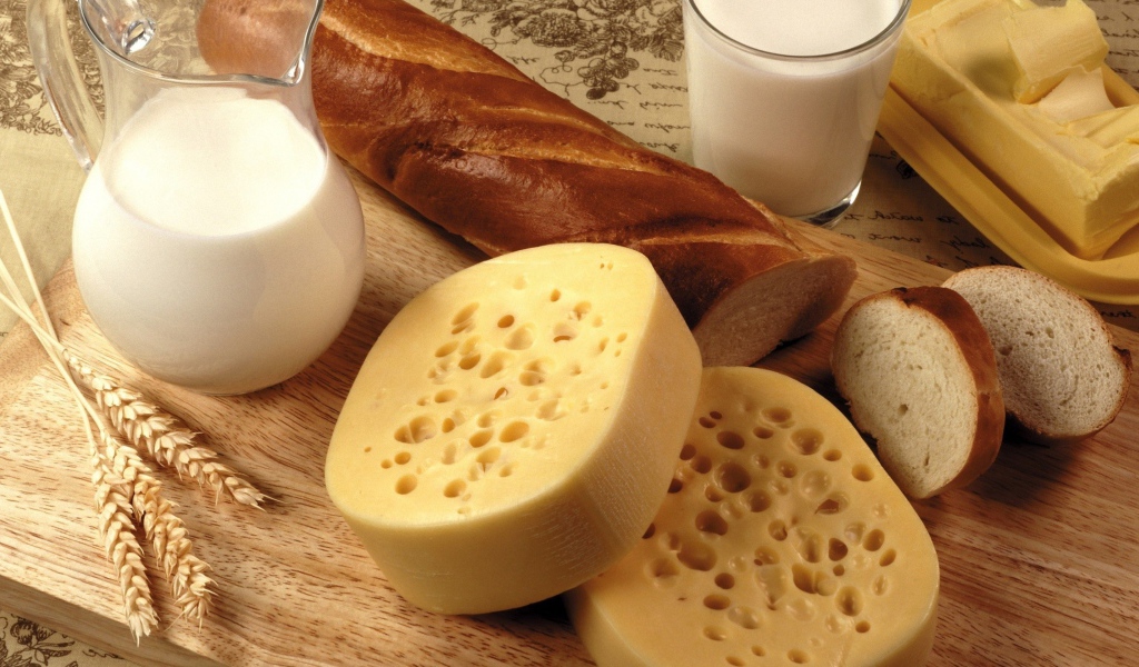 Сыр на столе с маслом, молоком и батоном 