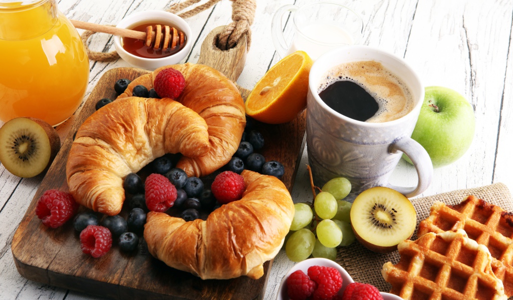 Круассаны с ягодами, на столе с кофе, медом и вафлями