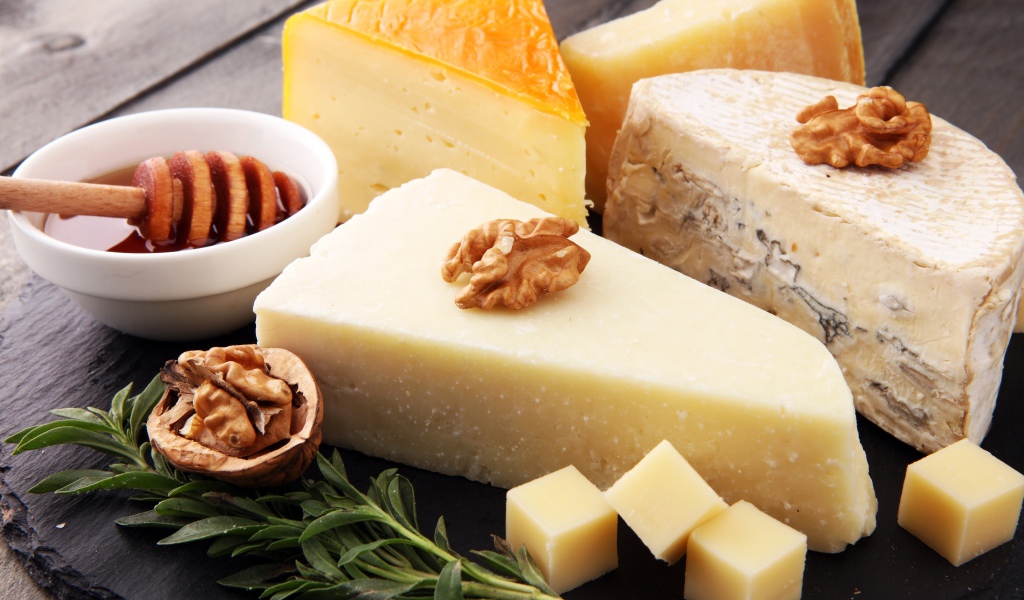 Разные виды сыра на столе с медом и грецкими орехами