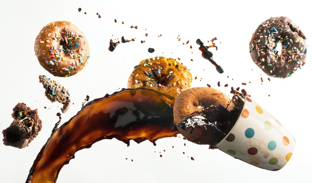 Пончики с чашкой кофе на белом фоне