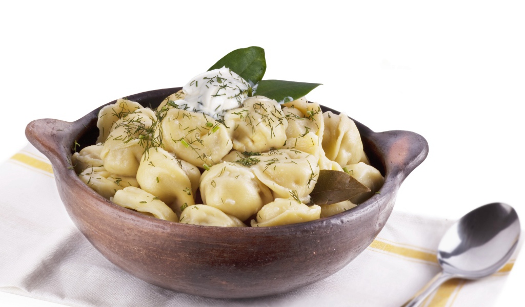 Пельмени в миске на белом фоне с ложкой 