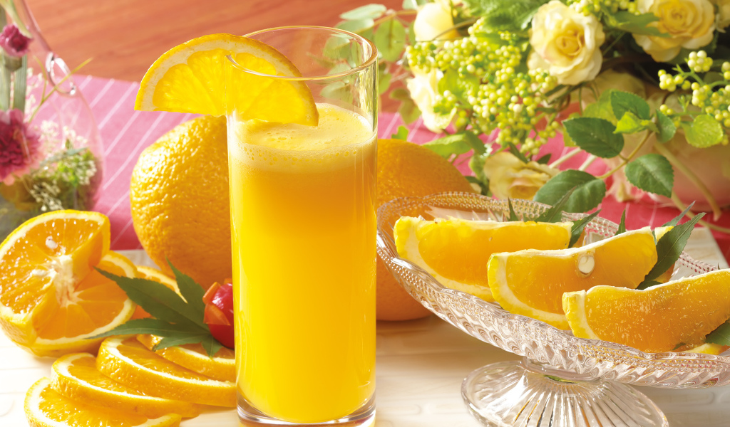 Fresh orange juice on the table with fruits and flowers