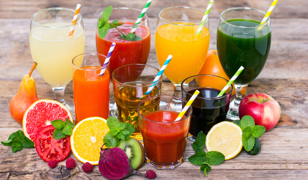 Свежевыжатые соки на столе с овощами и фруктами