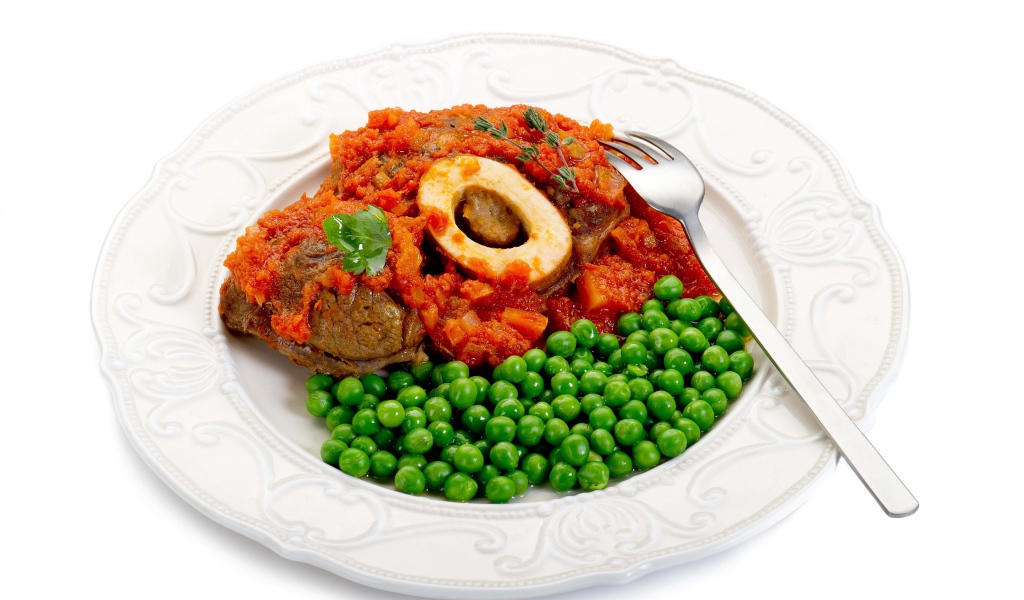 Зеленый горошек на белой тарелке с мясом