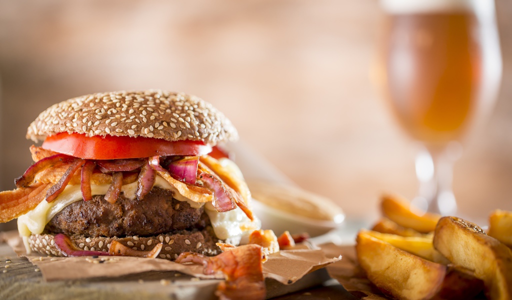 Гамбургер на столе с картофелем и бокалом пива