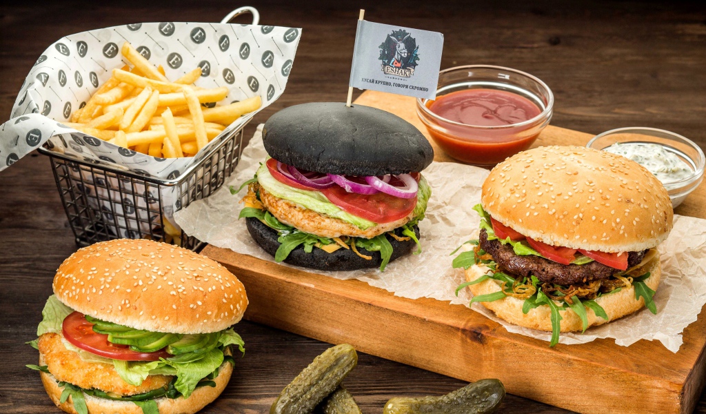 Гамбургеры с картофелем фри и солеными огурцами на столе 