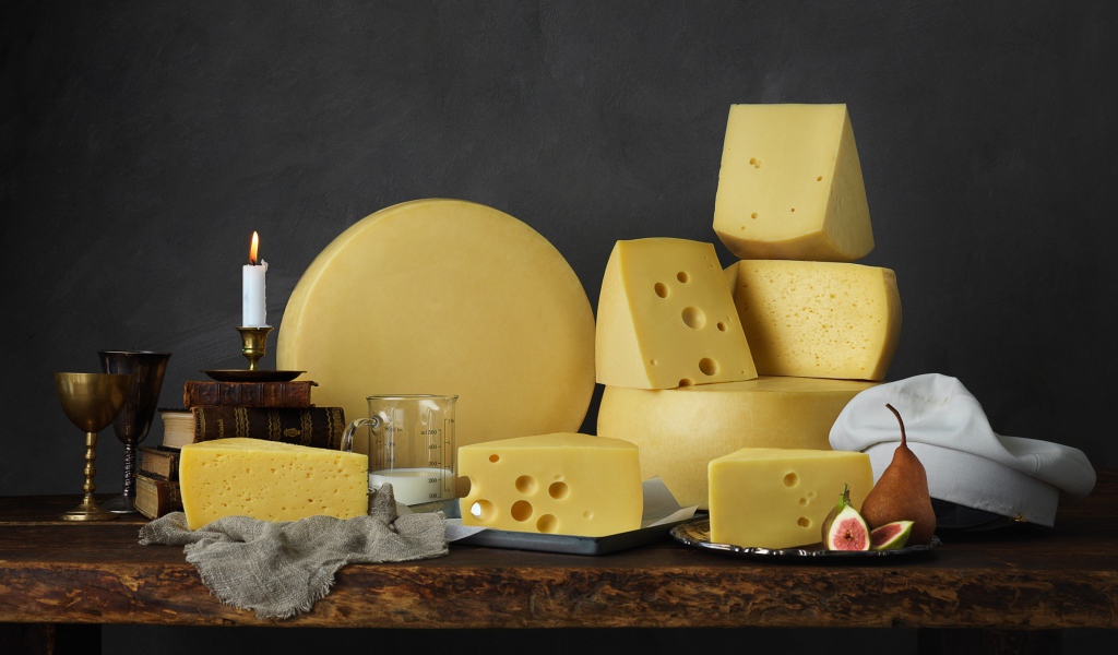 Твердый сыр на столе с книгами 