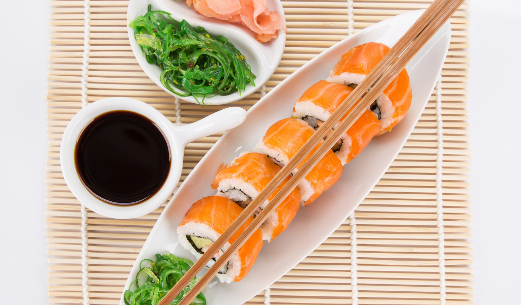 Японские суши на столе с соевым соусом и имбирем с салатом