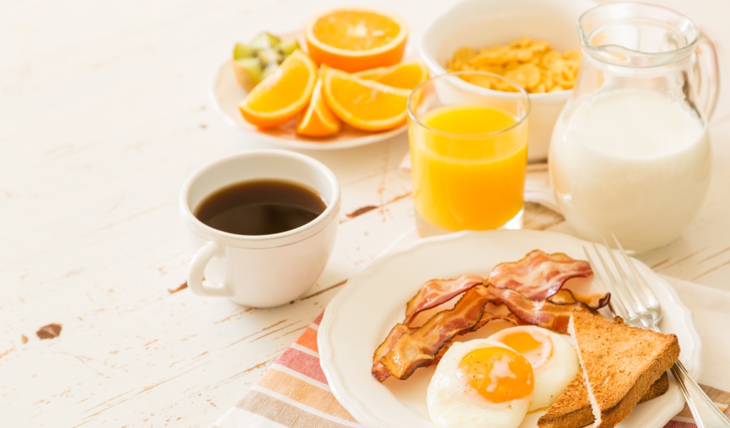 Сок, молоко, кофе, яичница и бекон на завтрак 